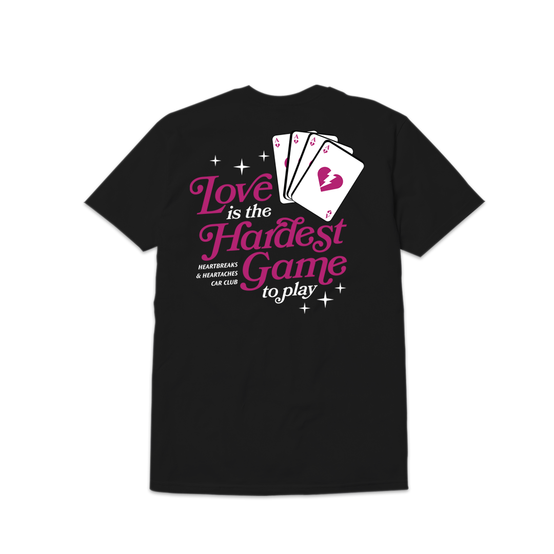 Black T-shirt featuring a graphic of playing cards, pink and white text reading Love is the Hardest Game to Play, with sparkles.