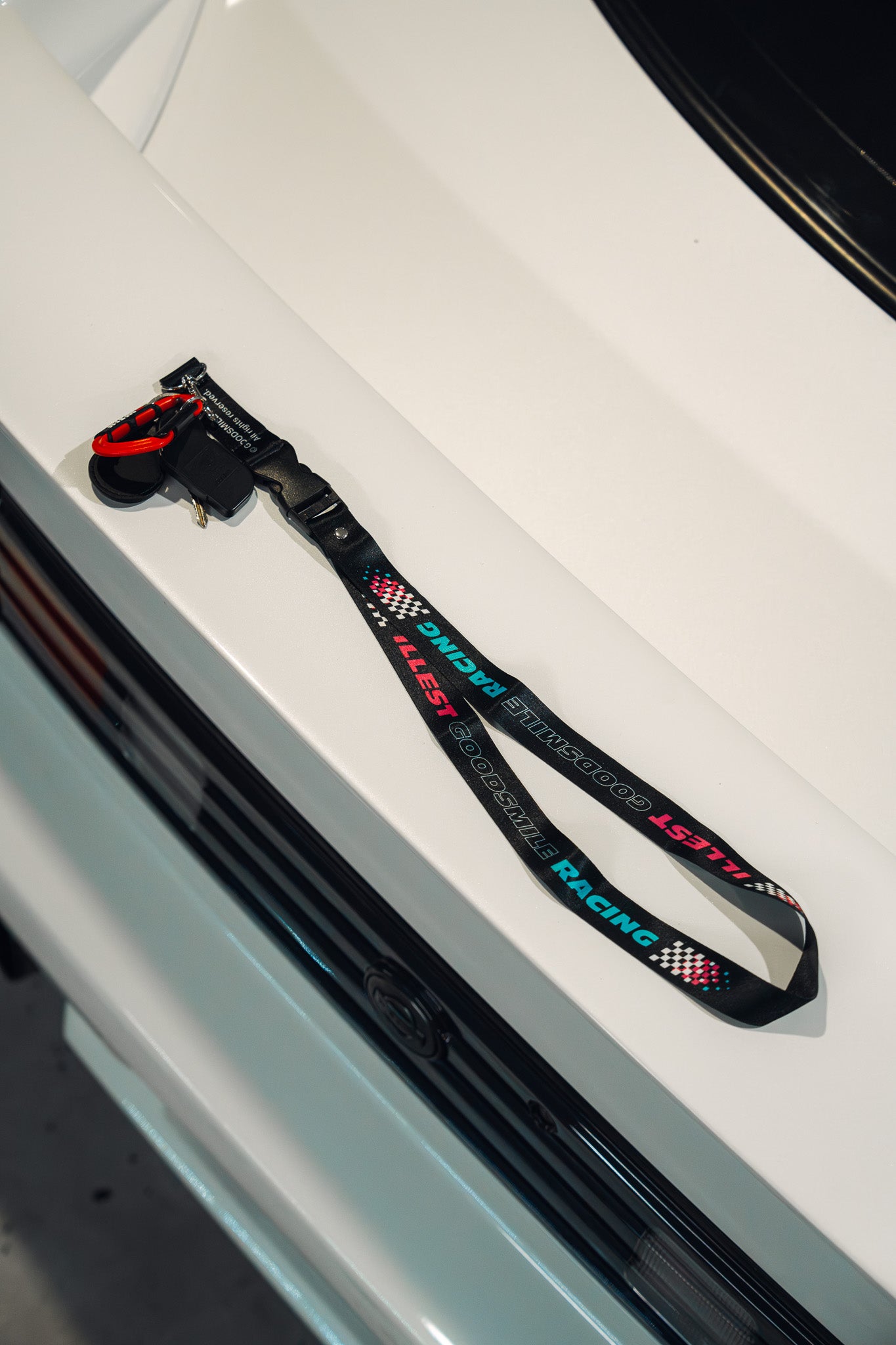 ILLEST x GOODSMILE GT lanyard featuring racing-themed text and checkered patterns, with a clip and red safety loop.