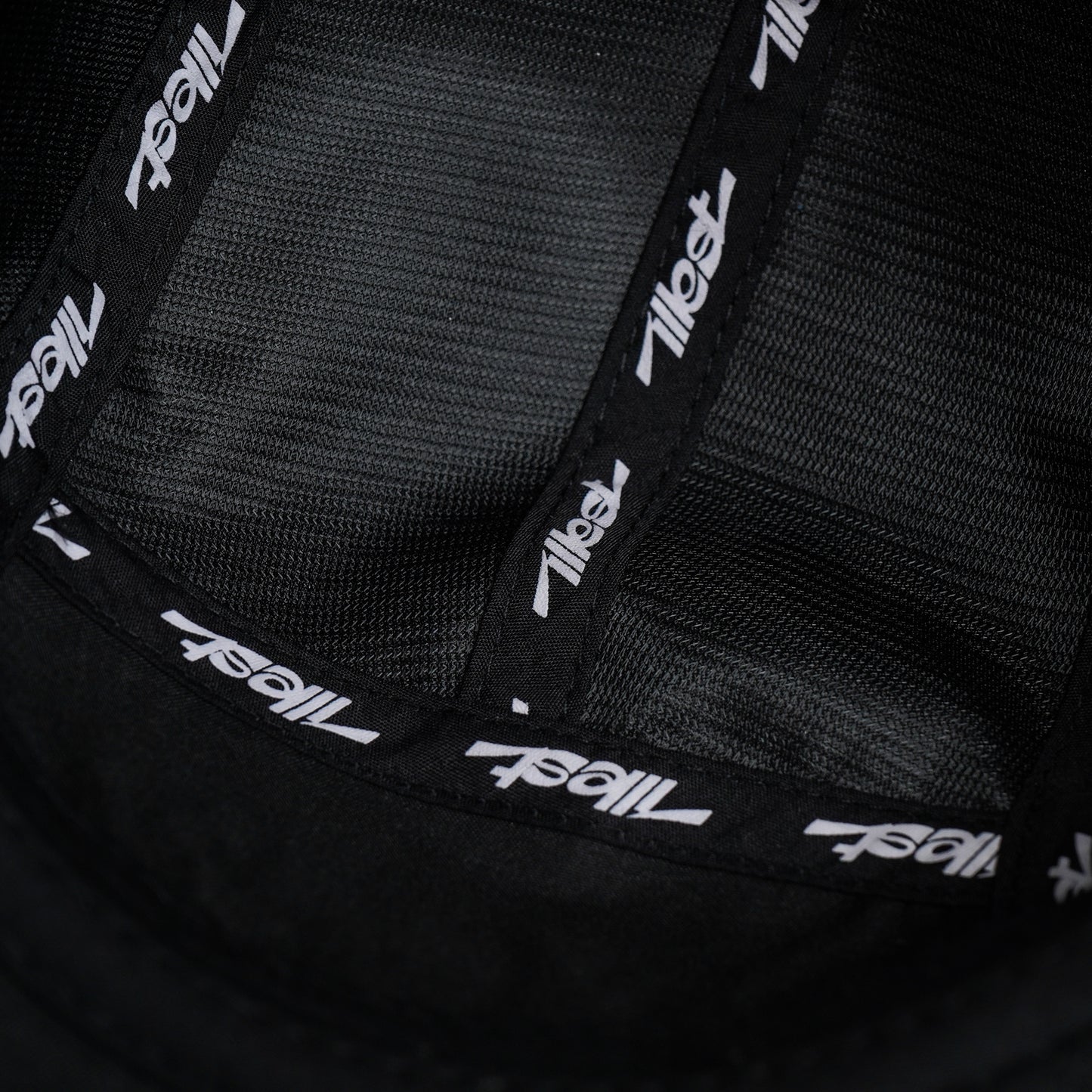 Close-up of a black Illest Essential five-panel cap interior with branded tape and mesh fabric.
