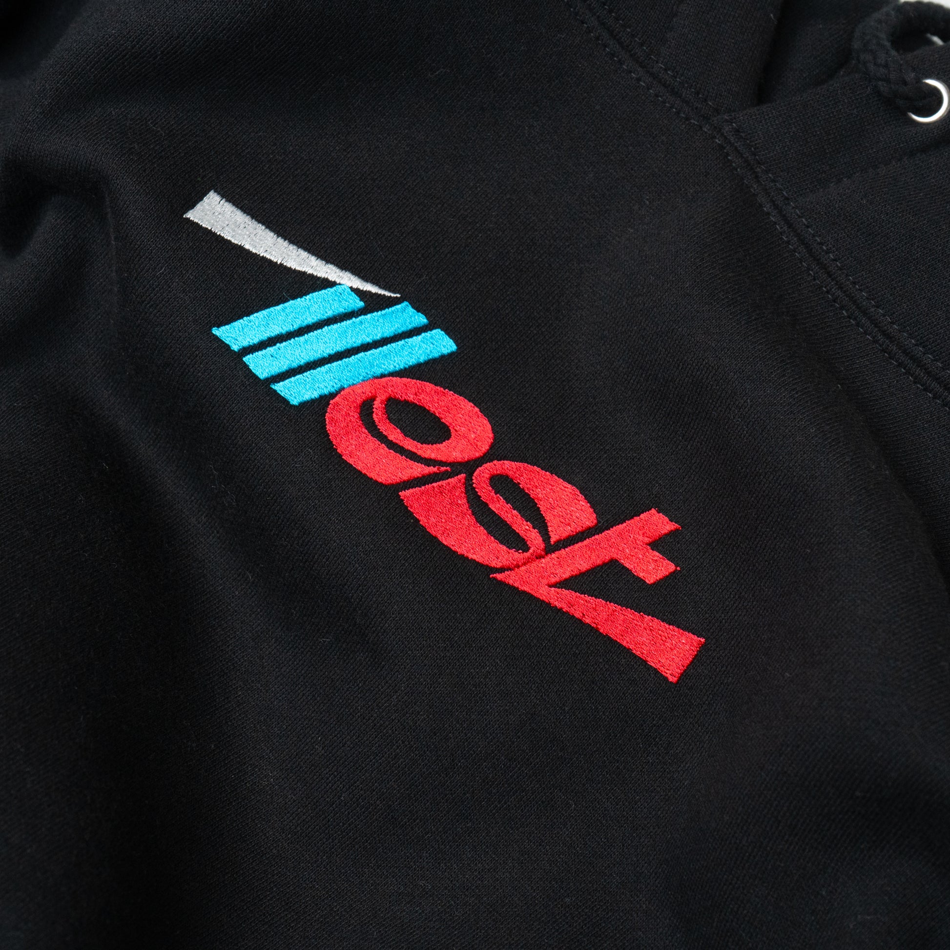 Black hoodie featuring embroidered Illest Essentials logo with red, blue, and white design elements.