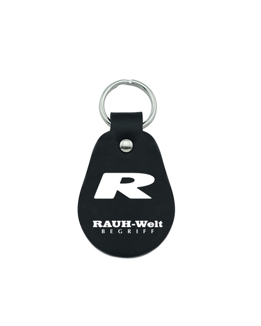 Black leather hotel keychain with a silver ring, featuring a bold white "R" and the text "Rauh-Welt Begriffe" printed below.