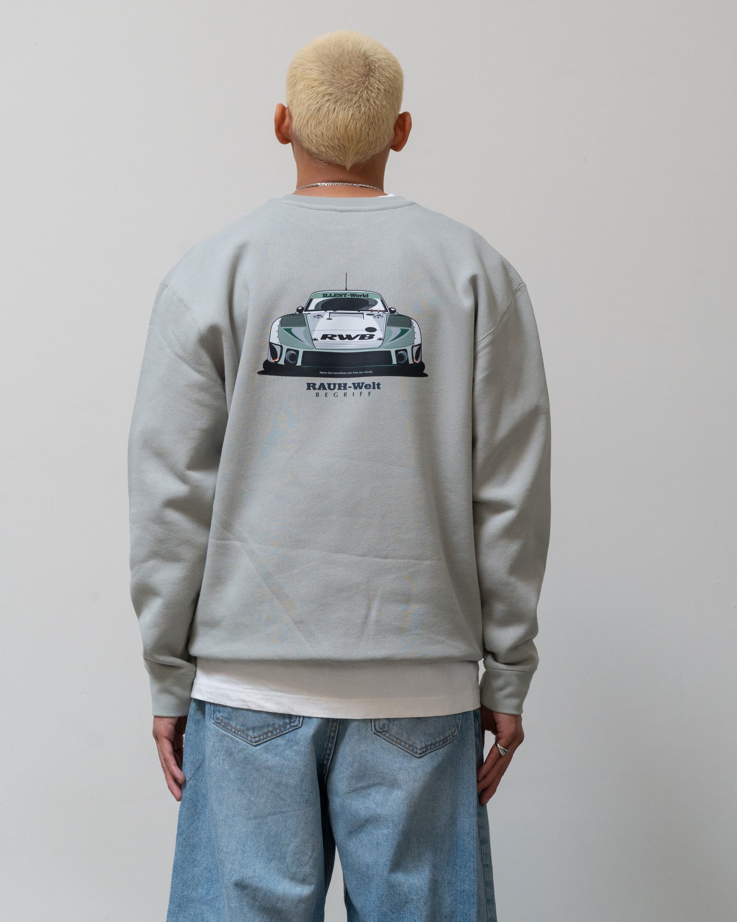 Back view of a person wearing a light gray crewneck sweatshirt featuring a graphic of a race car with "Rauh-Welt" and "RWB" text, and "Illest World" branding.