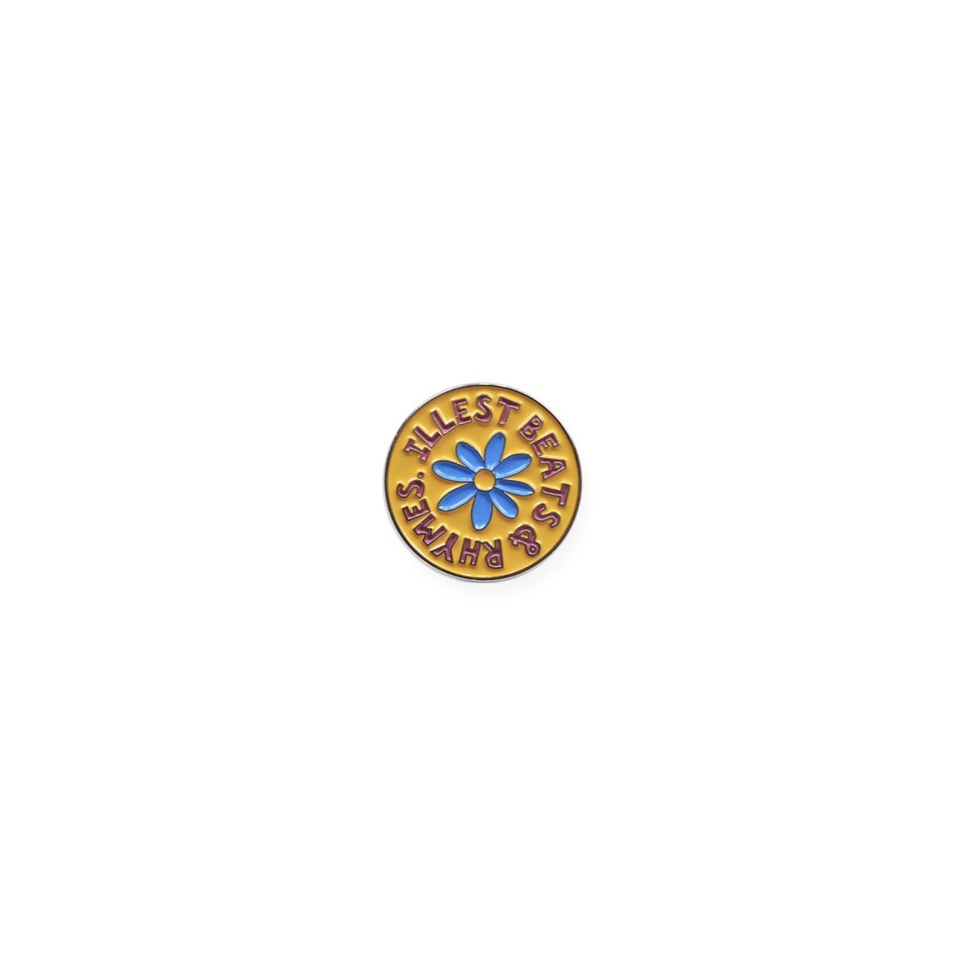 De La Daisy pin featuring a blue daisy flower and the phrase "Ilest Beas & Rhemess" on a yellow background.