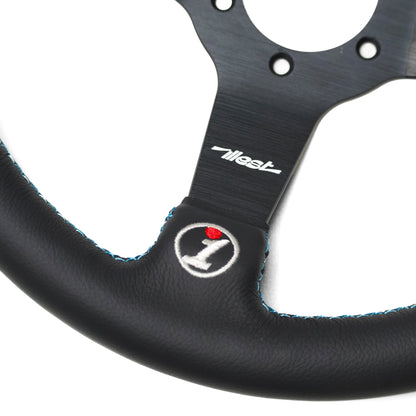 Close-up of the Since Forever Steering Wheel with a black leather grip, blue stitching, and a logo embroidered at the bottom.