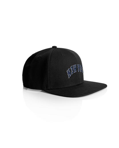 Black snapback cap with "New York" embroidered in blue and white on the front, featuring a flat brim and adjustable strap.