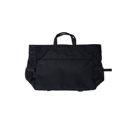 Black travel tote bag with handles, side mesh pockets, and adjustable straps, ideal for carrying essentials during trips.