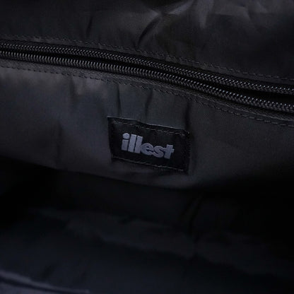 Close-up of a black Illest Travel Tote Bag interior showing a stitched Illest logo tag and a zippered pocket.