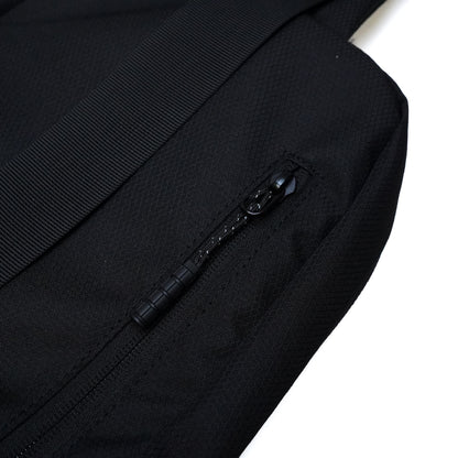 Close-up of a black Illest Crossbody Bag showing textured fabric and a zipper pocket with a black pull tab.