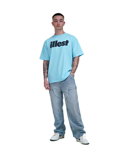 Young man wearing a light blue Illest Bold Logo Miami Blue T-shirt, light-wash baggy jeans, and white sneakers, standing against a white background.