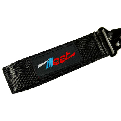 Black fabric keychain with a colorful ILLEST logo patch, featuring a clip for attaching keys or accessories.