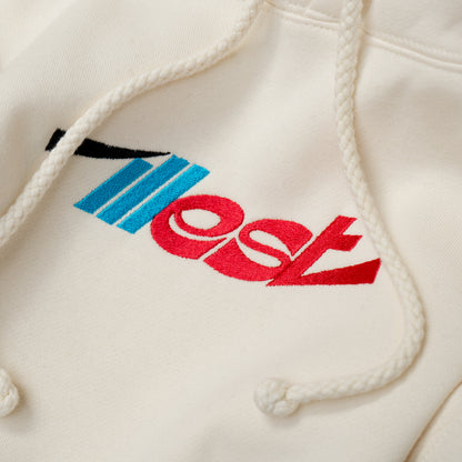 Close-up of a cream-colored hoodie featuring embroidered Illest Essentials logo with red, blue, and black details and white drawstrings.