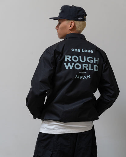 Back view of a person wearing a black Illest Rough-World Coach Jacket with large light blue text reading "one Love Rough World Japan" on the back.